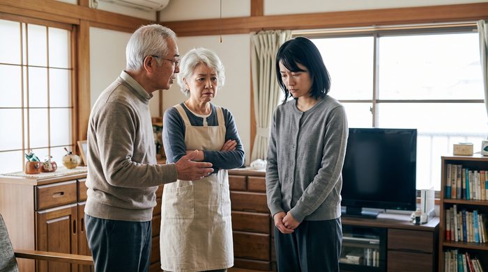 休職中の女性が両親から怠けていると叱られている