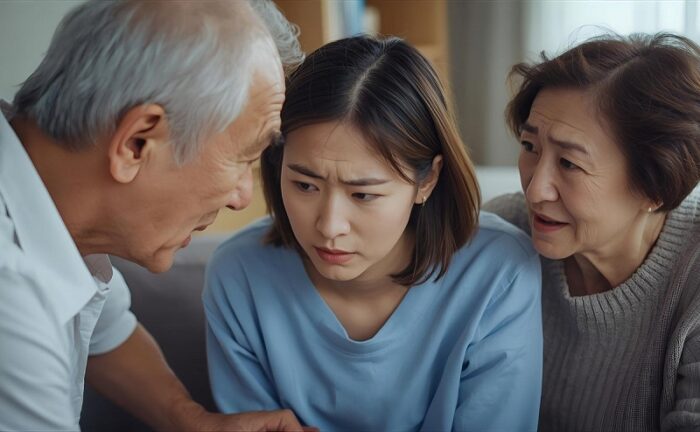 両親から叱責される女性