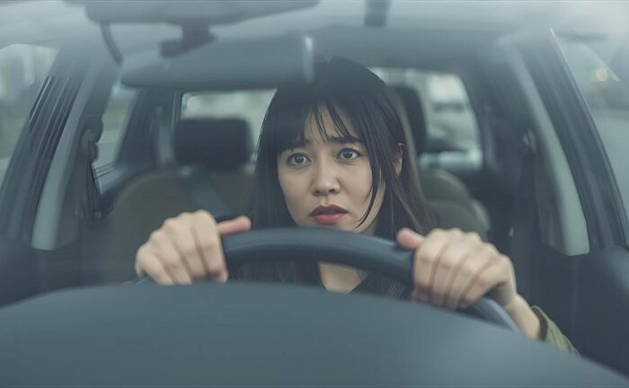 苦しそうな表情で車を運転する女性